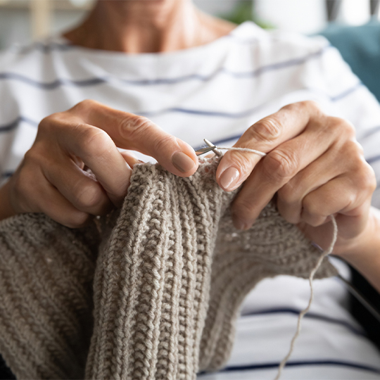 Close up view grandmothers hands holding needles and knitting